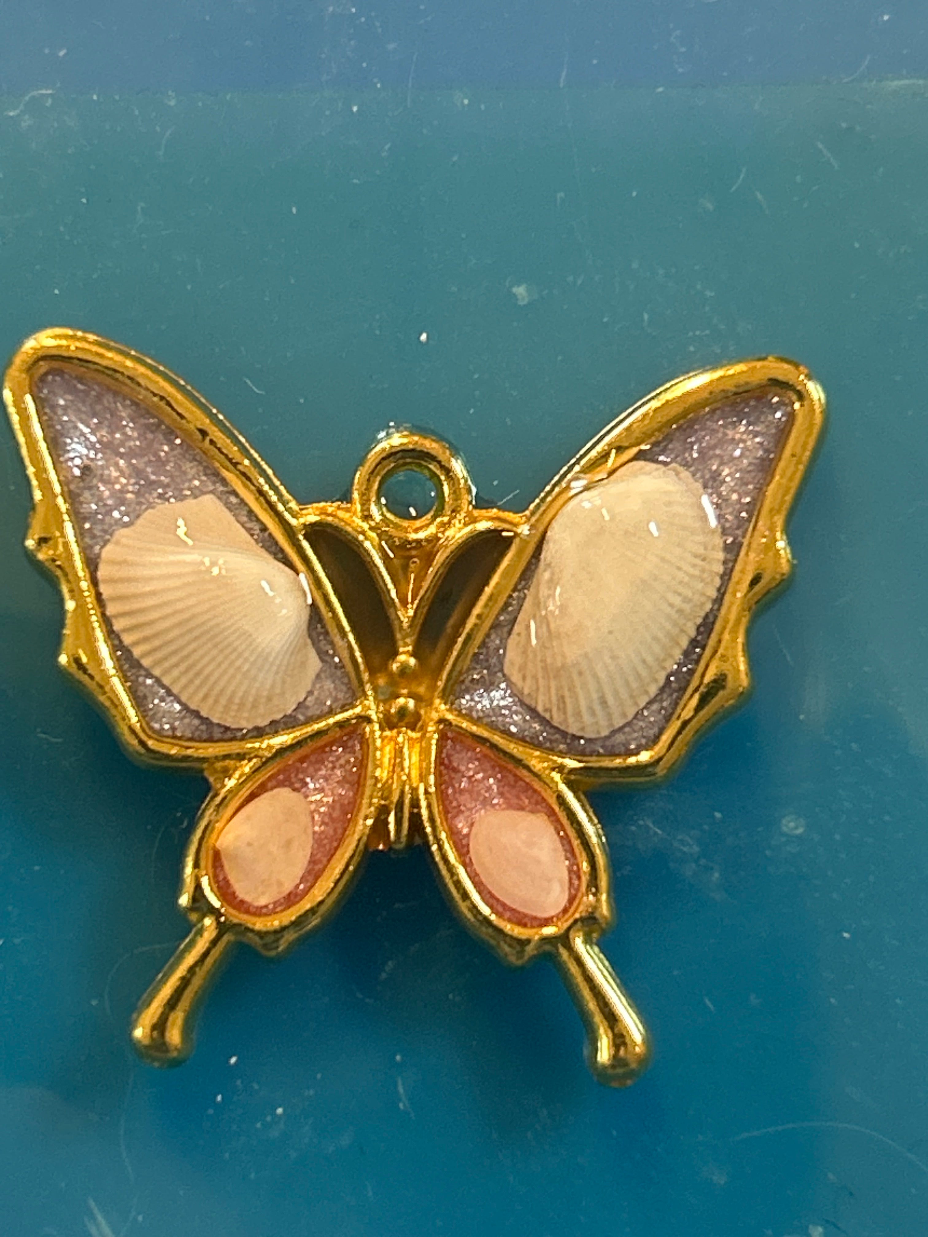 Butterfly-shaped pendant with shell inclusions on a blue background