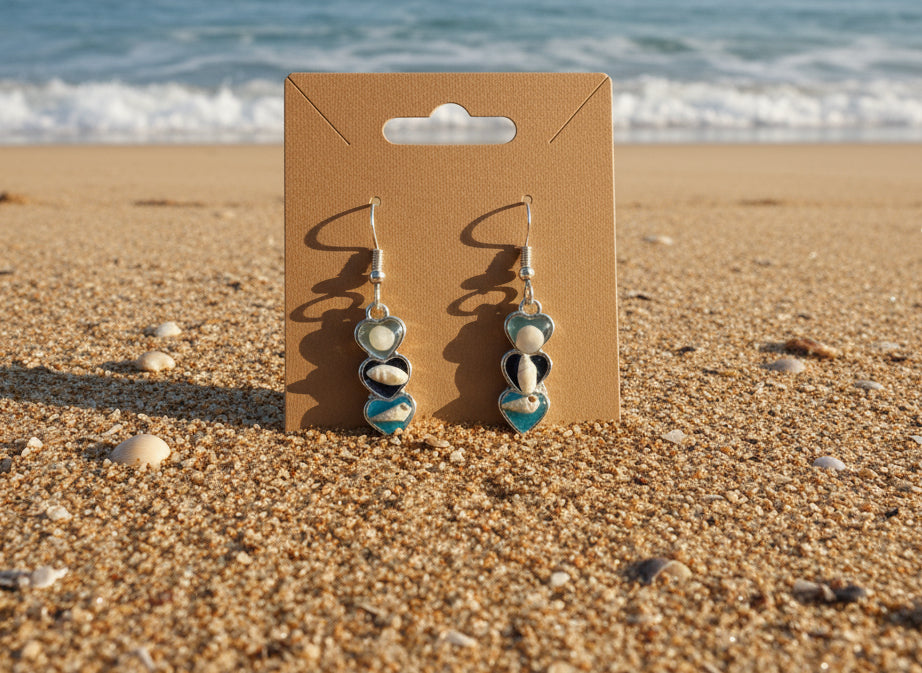 silver hearts with tiny shells on sandy beach
